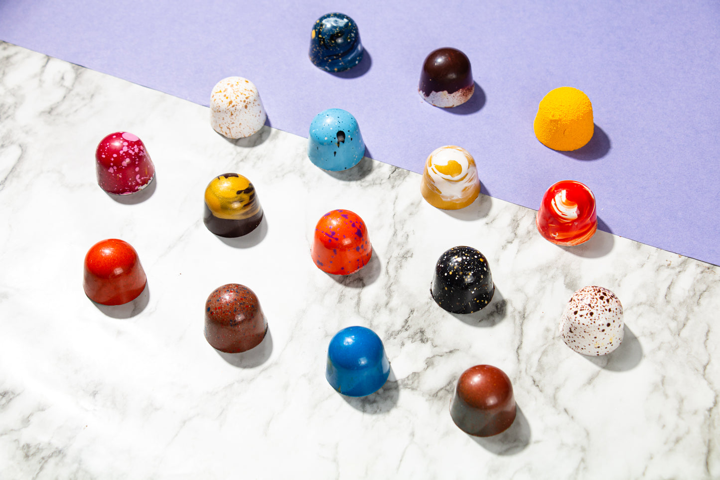 A variety of chocolate bonbons on a marble and purple backdrop