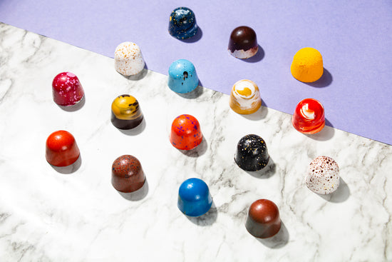 Multiple colourful chocolate bonbons on a marble and purple backdrop